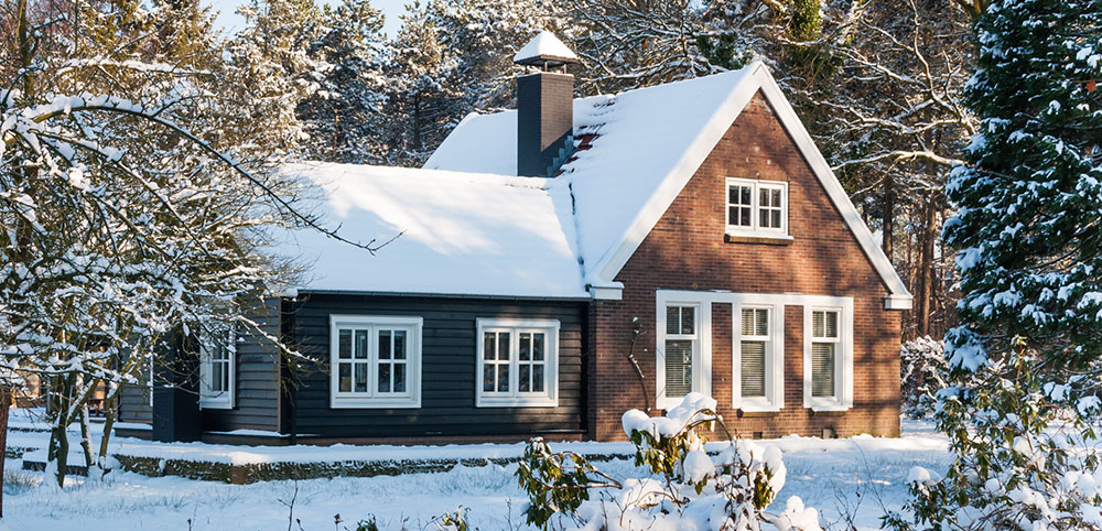 Snow covered home and grounds in wooded setting